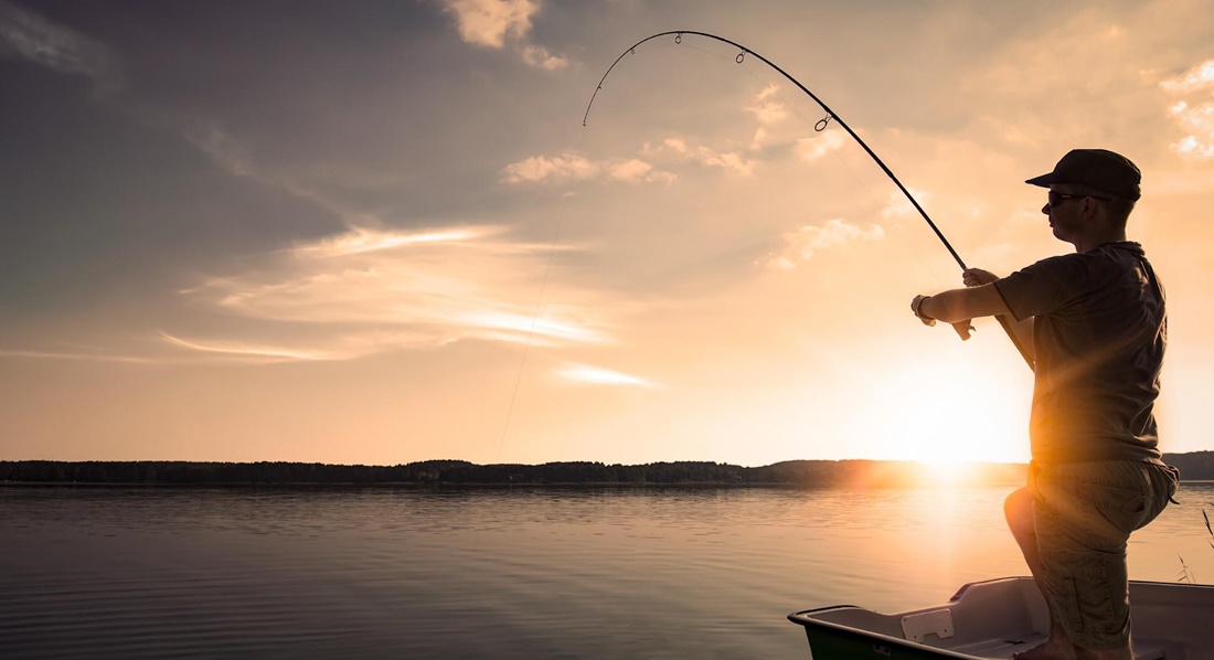 Angler im Boot vor Sonnenaufgang hat etwas gefangen