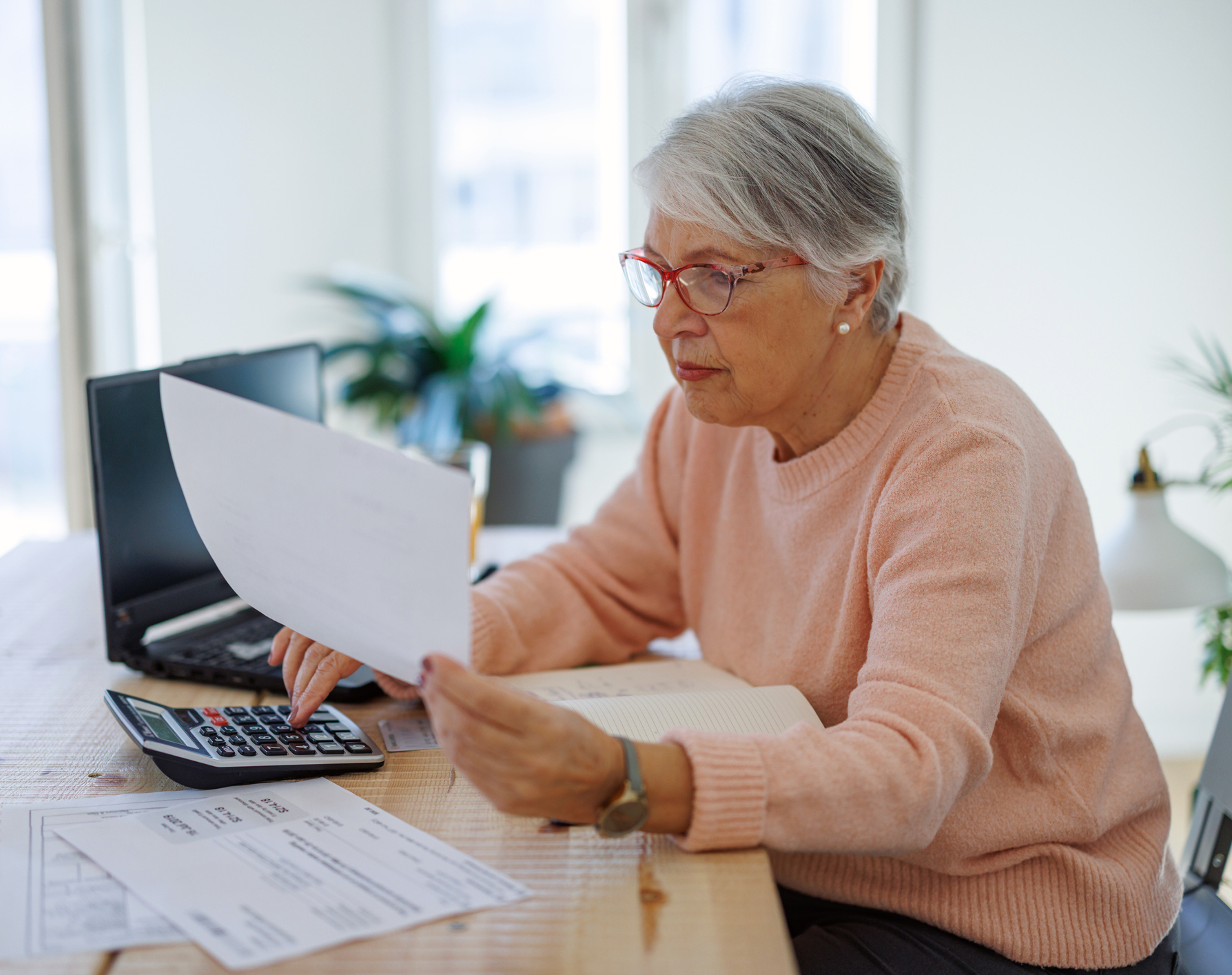 Ältere Frau prüft konzentriert ihre Nebenkostenabrechnung
