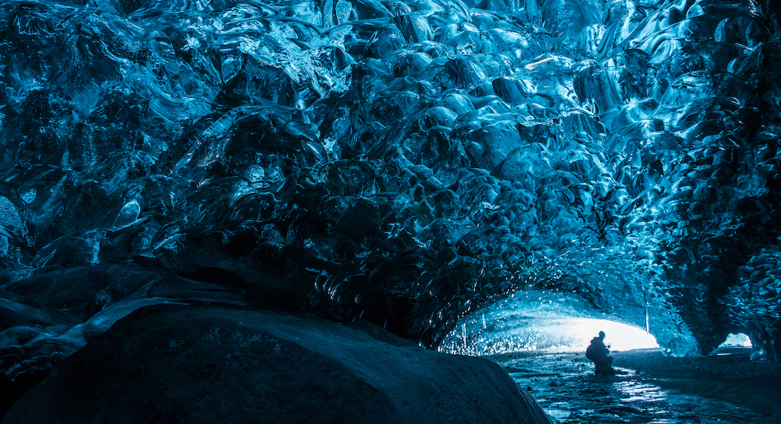 Besucher in der Vatnajökull-Höhle auf Island, über ihm Gletscher in leuchtendem Türkis