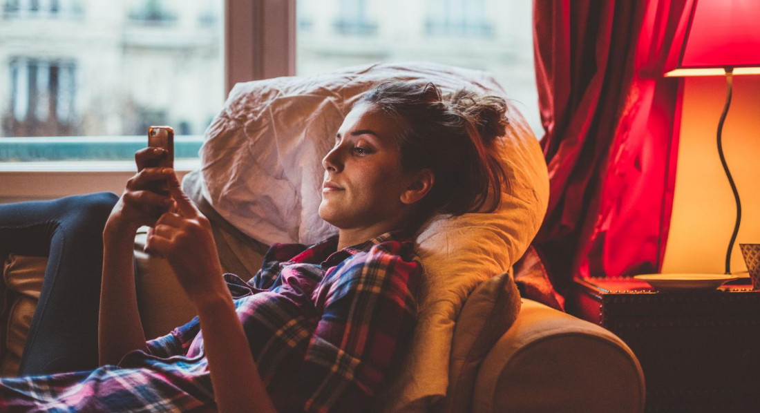 Eine Frau mit Smartphone auf dem Sofa