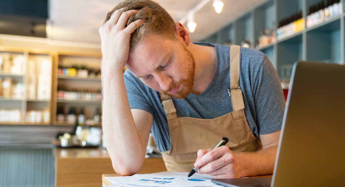 Arbeiter berechnet mit Stift und Laptop sein Kurzarbeitergeld