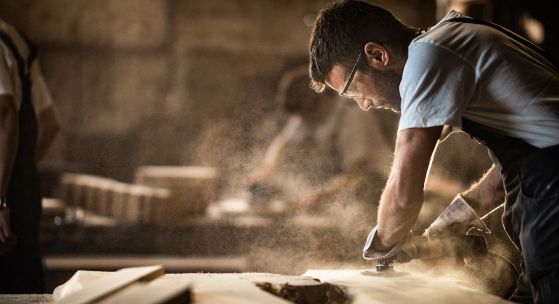 Tischler bearbeitet Holz mit einem Schleifgerät