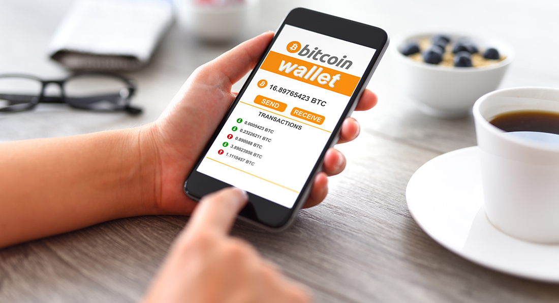 Finger tippt auf ein Handy-Display, das eine Bitcoin-Wallet zeigt