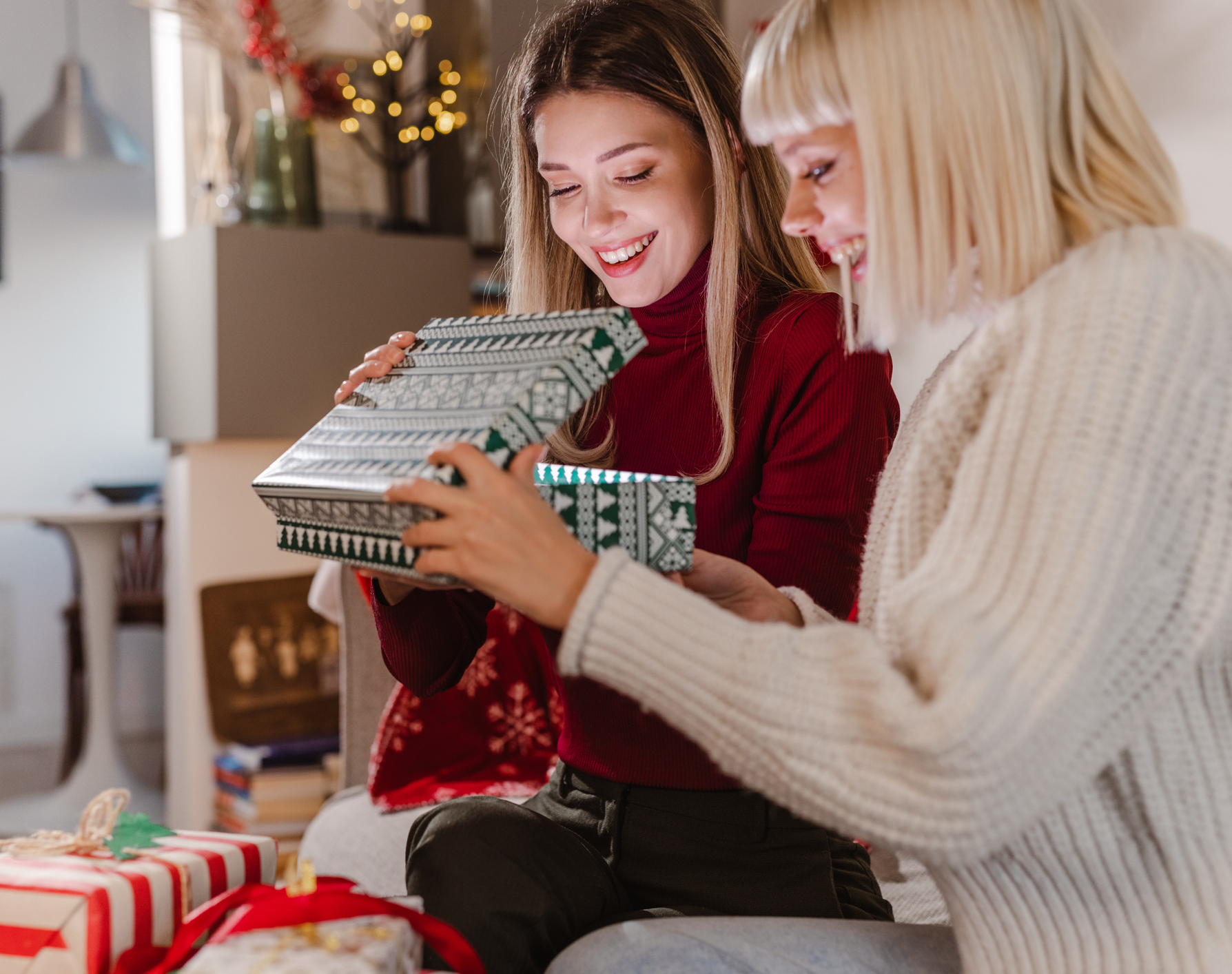 Junge Frauen öffnen Weihnachtsgeschenke zu Hause