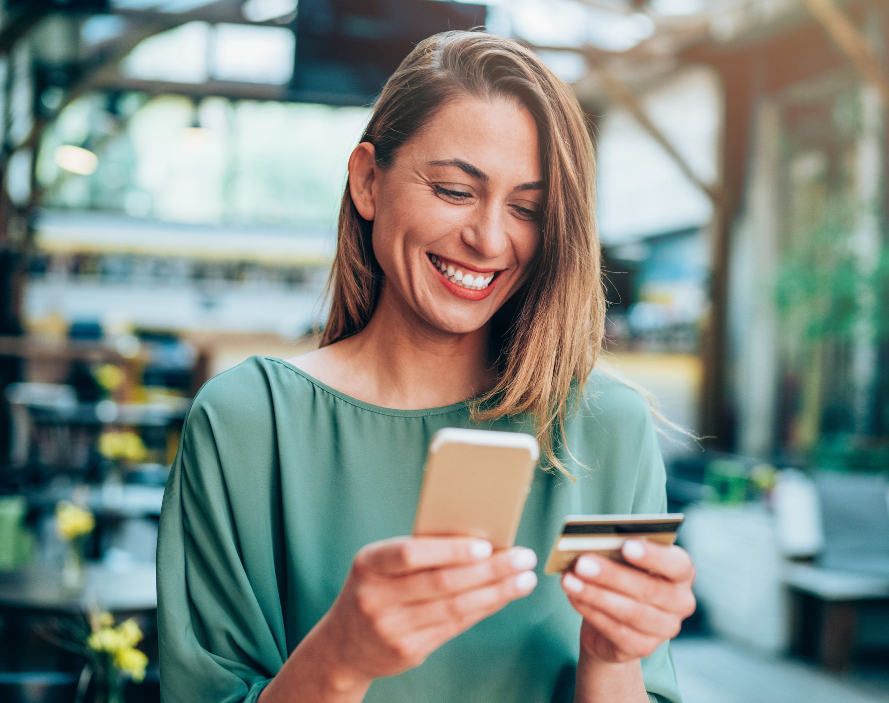 Eine Frau hält eine Bankkarte und ein Smartphone in den Händen