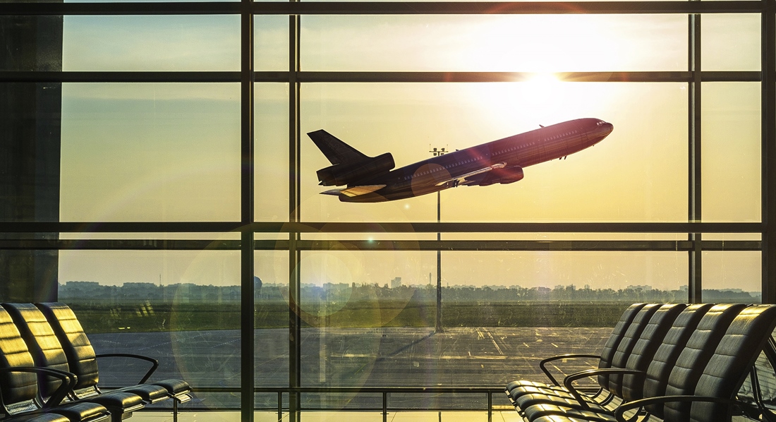 Blick aus einem leeren Flughafen Terminal auf ein abhebendes Flugzeug