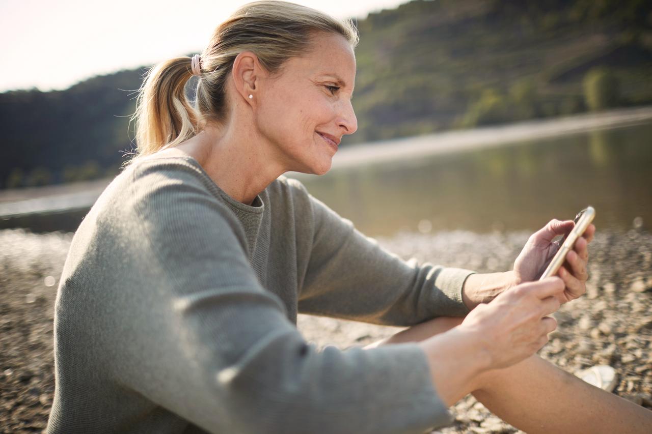 Frau am Strand, die einen SparBrief der Hanseatic Bank online beantragt