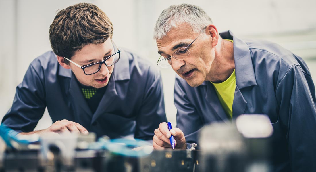 Ingenieur erklärt seinem Schüler die Funktionsweise einer Maschine