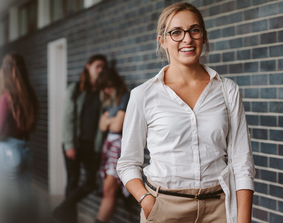 Junge lächelnde Frau auf dem Flur eines Universitätsgebäudes