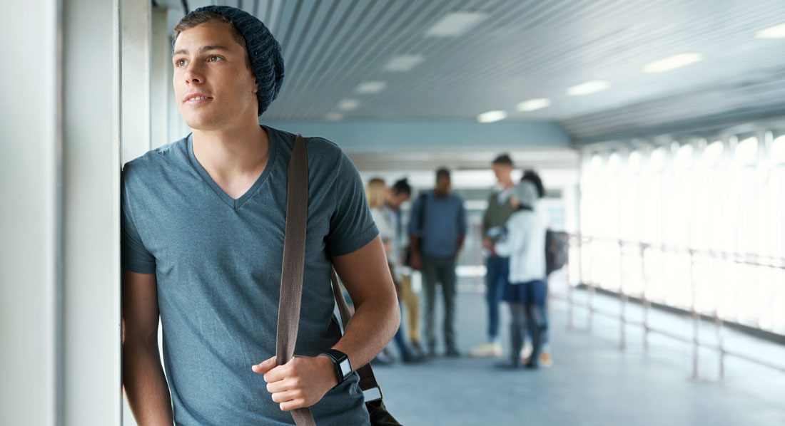 Student blickt nachdenklich aus dem Fenster eines Universitätsgebäudes