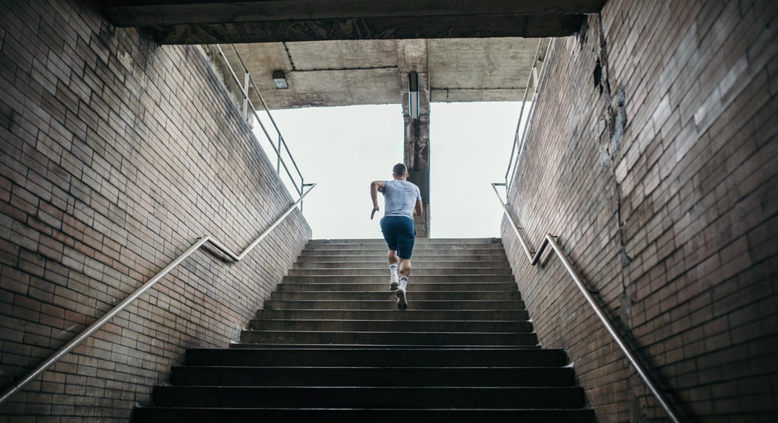 Ein Mann im Sportdress läuft eine lange Treppe hinauf