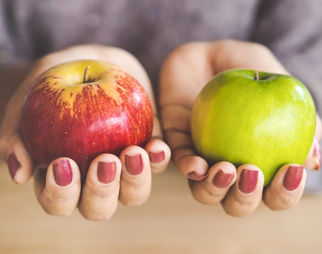 Unterschied Festgeld und Sparbrief: Eine Frau hält je einen roten und einen grünen Apfel in der Hand