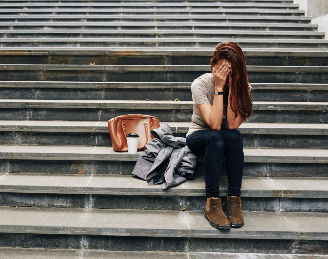 Junge Frau sitzt verzweifelt auf einer öffentlichen Treppe
