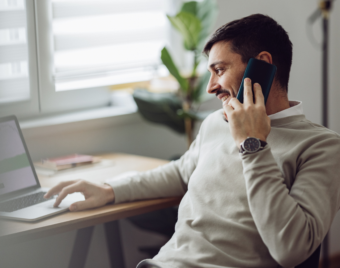 Ein Mann telefoniert mit dem Blick auf seinen Laptop