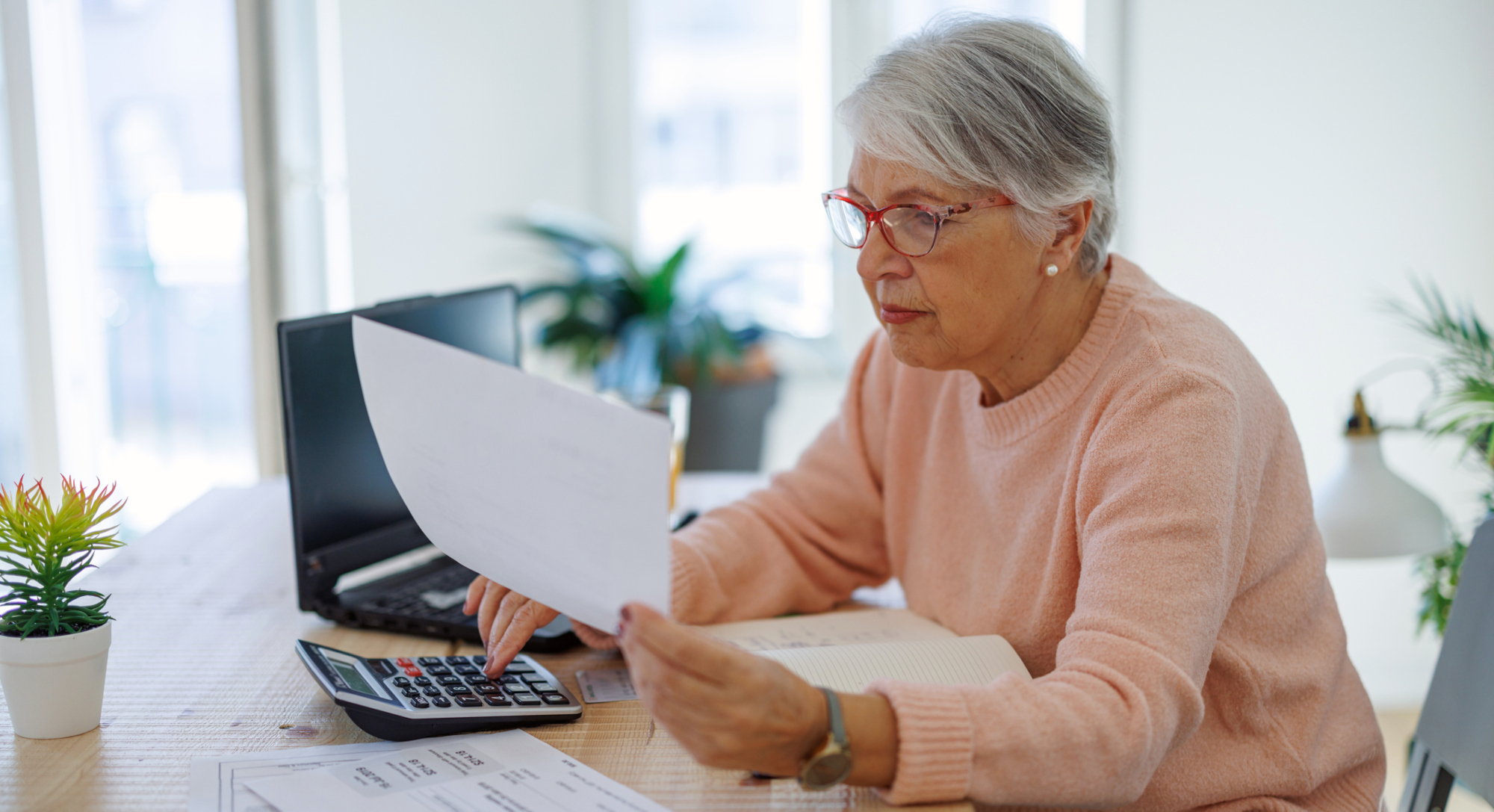 Ältere Frau prüft konzentriert ihre Nebenkostenabrechnung