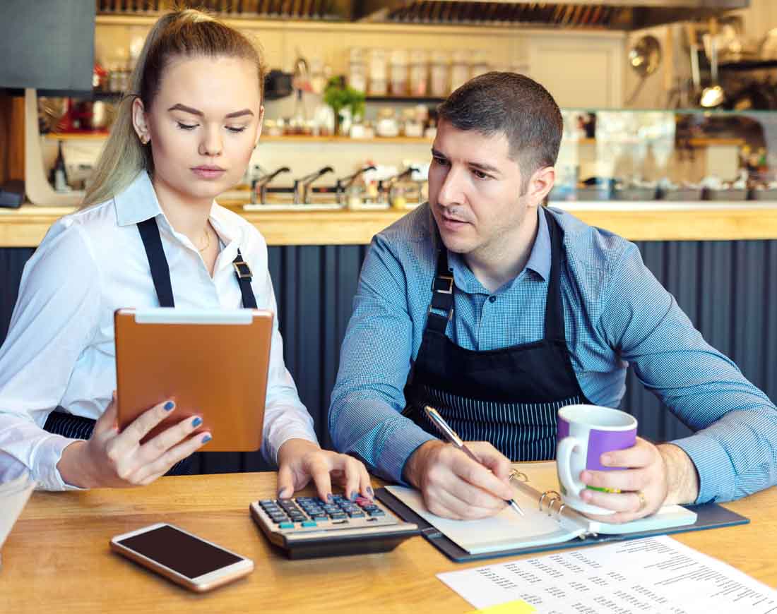 Junges Paar am Tisch ihres Restaurants kalkulieren die Zuschüsse zur Selbstständigkeit