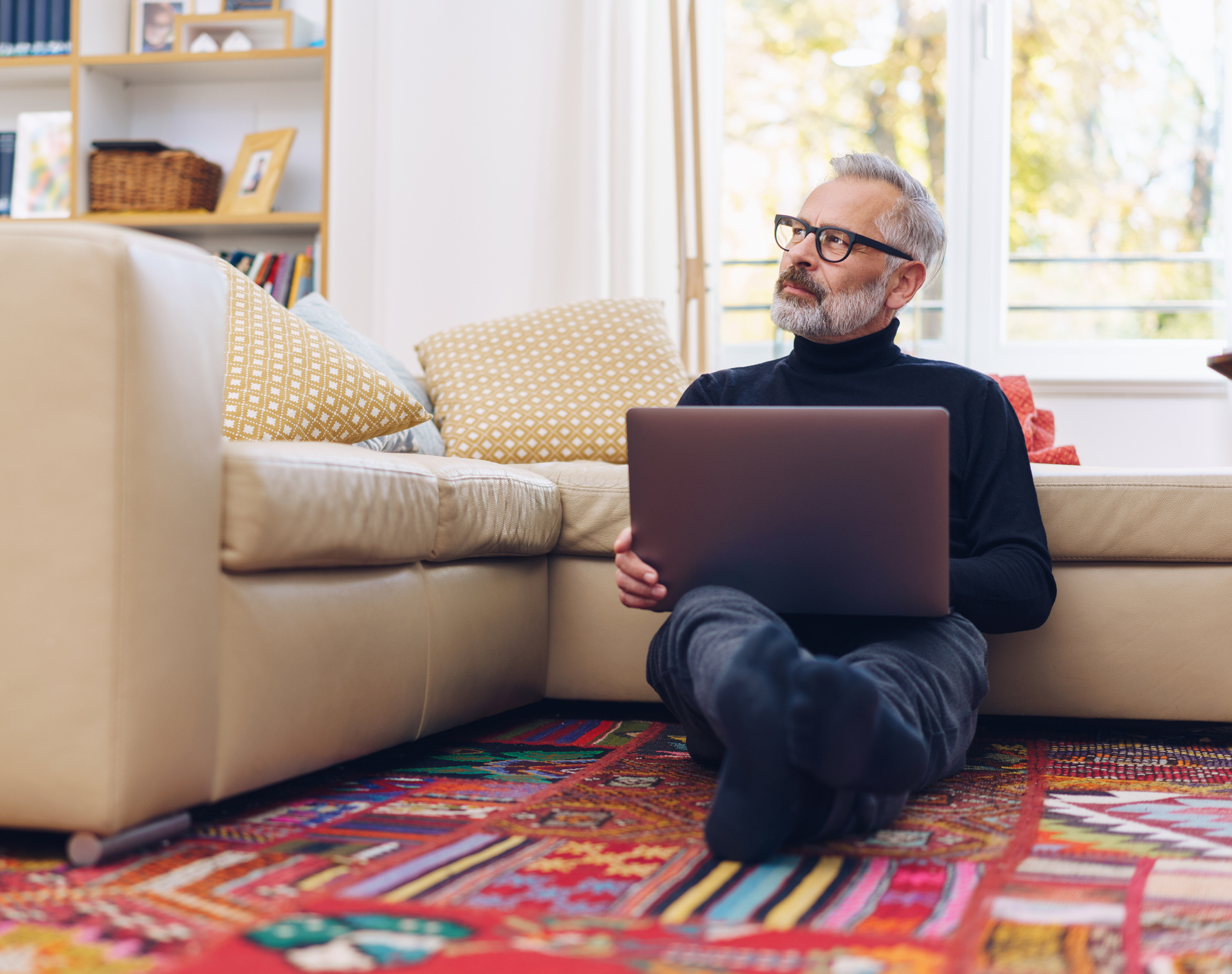 Ein Mann arbeitet auf dem Boden eines Wohnzimmers auf einem Laptop