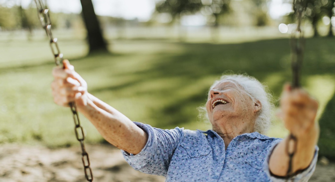 Fröhliche Seniorin auf einer Kinderschaukel