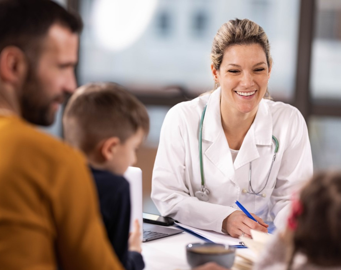 Eine freundliche Ärztin spricht in ihrer Praxis mit einer Familie