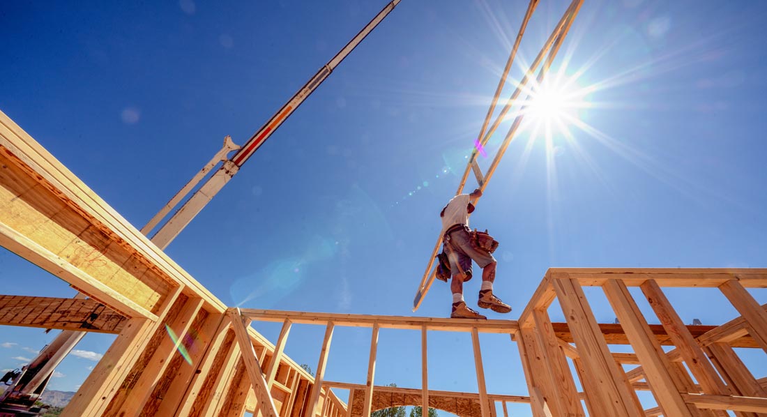 Dachdecker balanciert über ein Holzgerüst