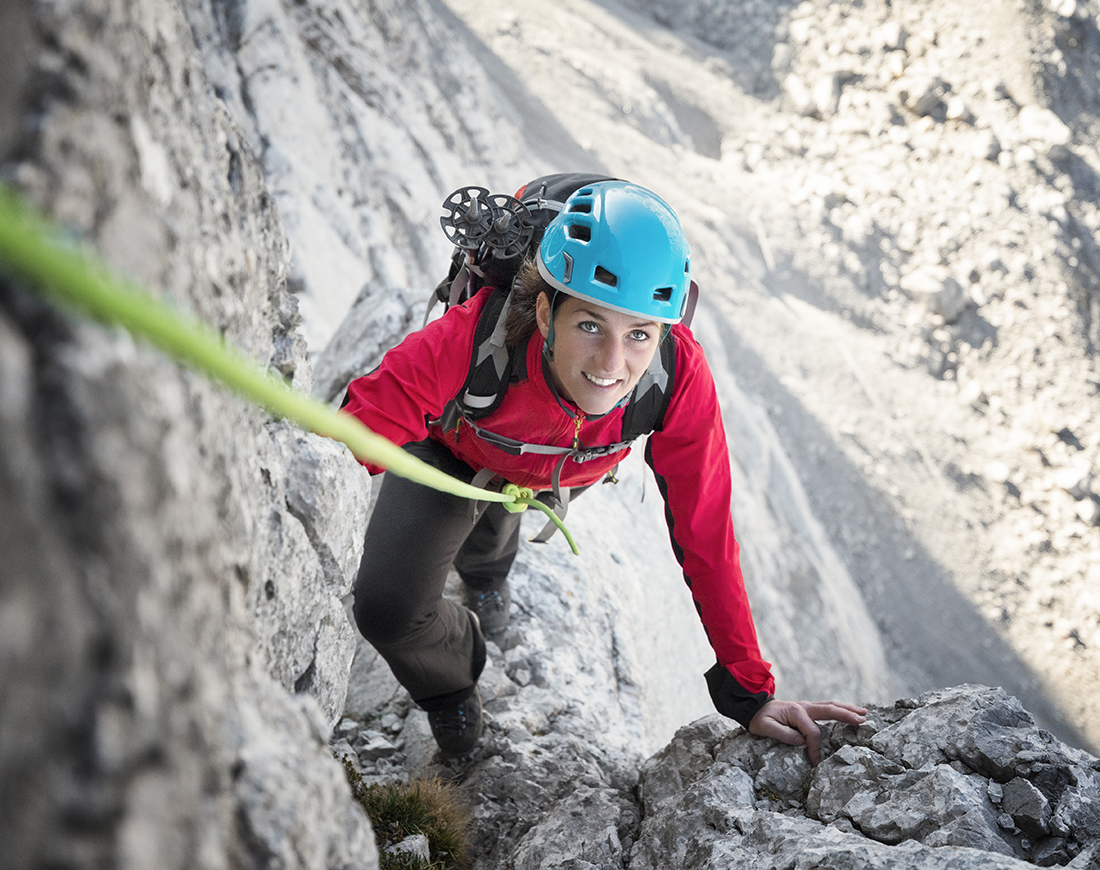 Eine Frau klettert gesichert an einem Seil einen Steilhang hinauf