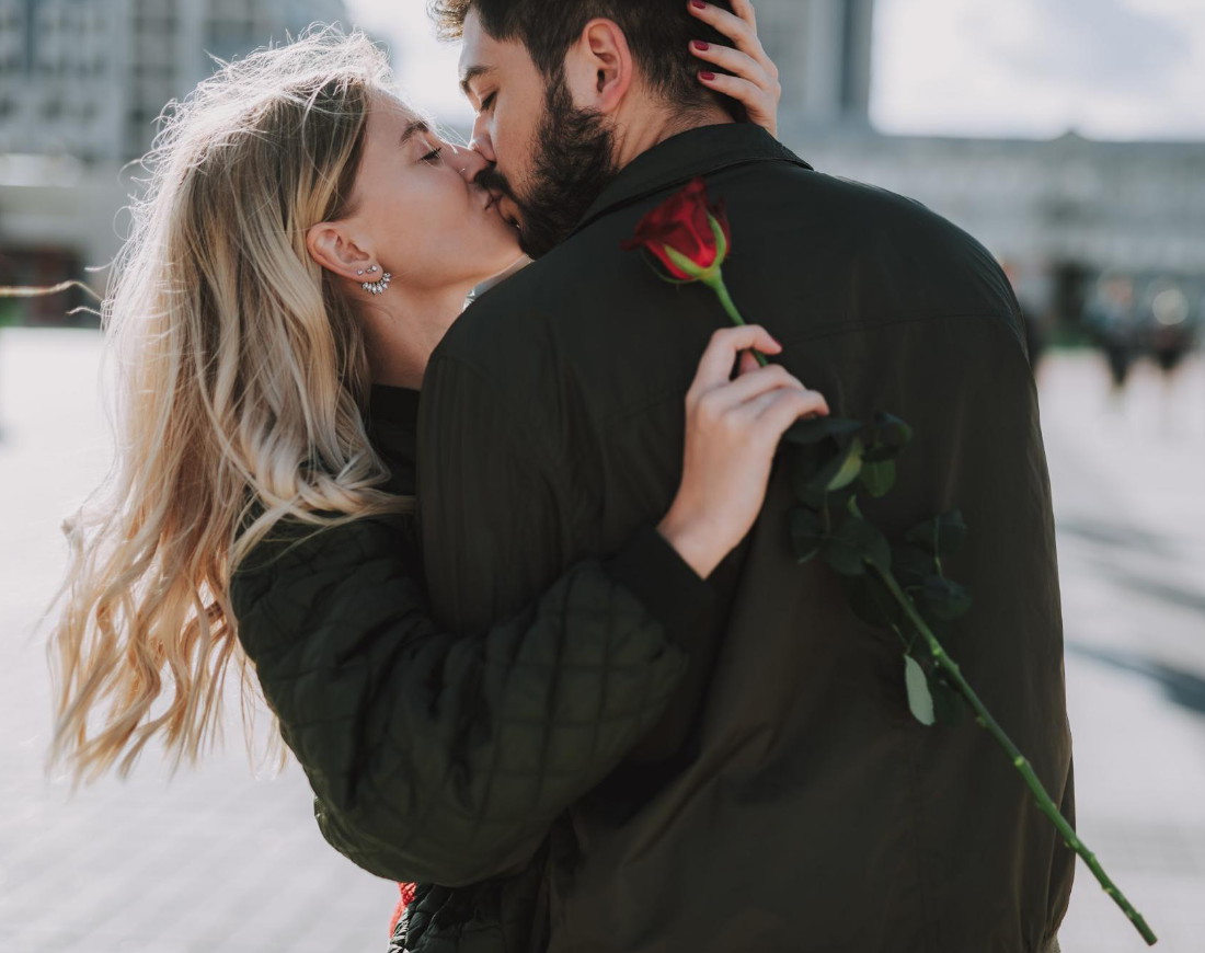 Eine Frau erhält vom Mann eine Rose zum Valentinstag und küsst ihn