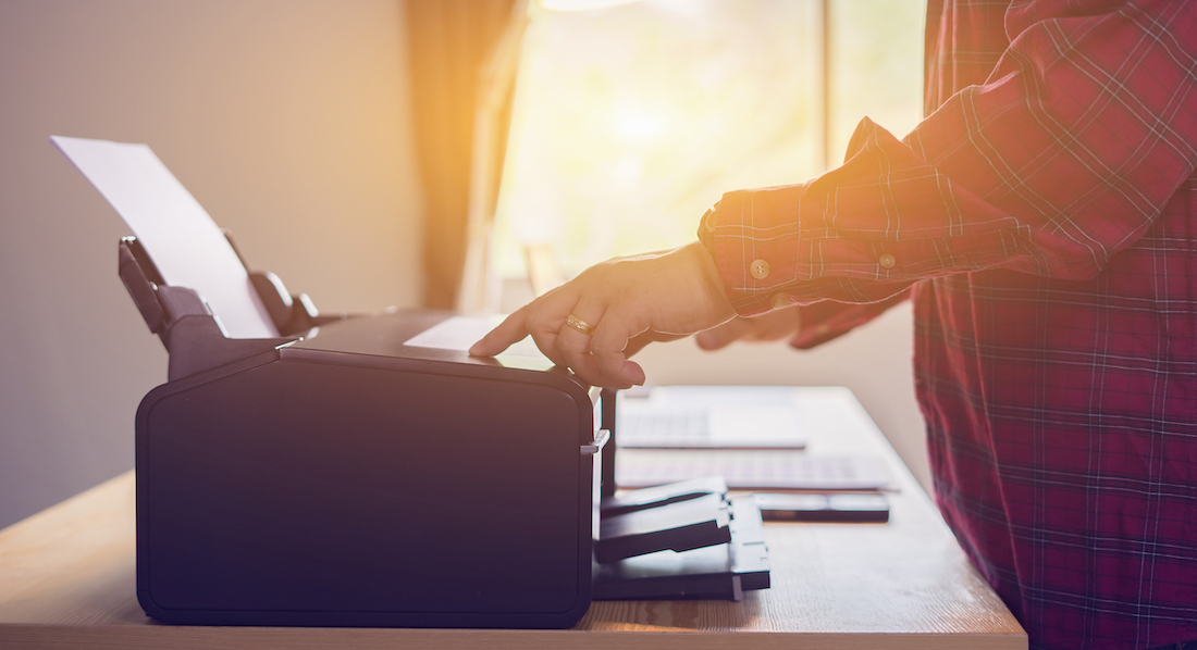 Ein Mann bedient einen Drucker, um eine Vorlage zur Kündigung seiner Versicherung auszudrucken