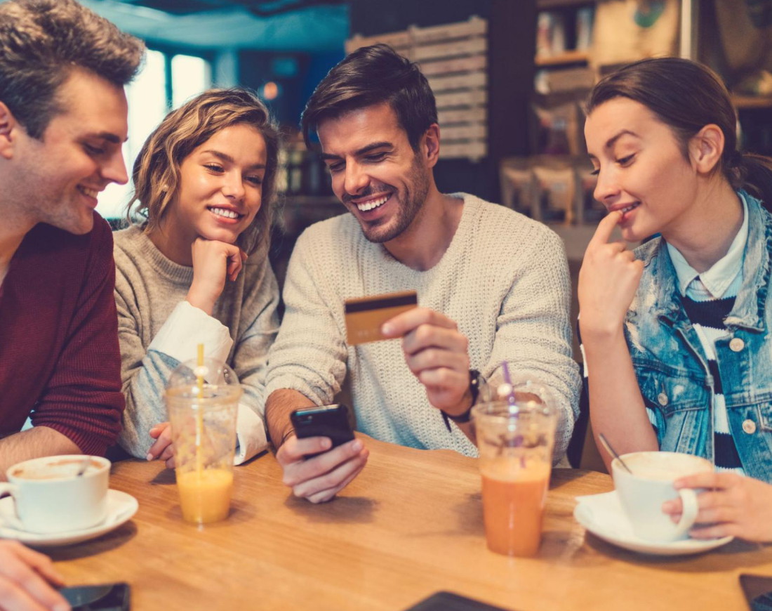 Eine Gruppe von Freunden kauft etwas auf dem Smartphone mit der Kreditkarte
