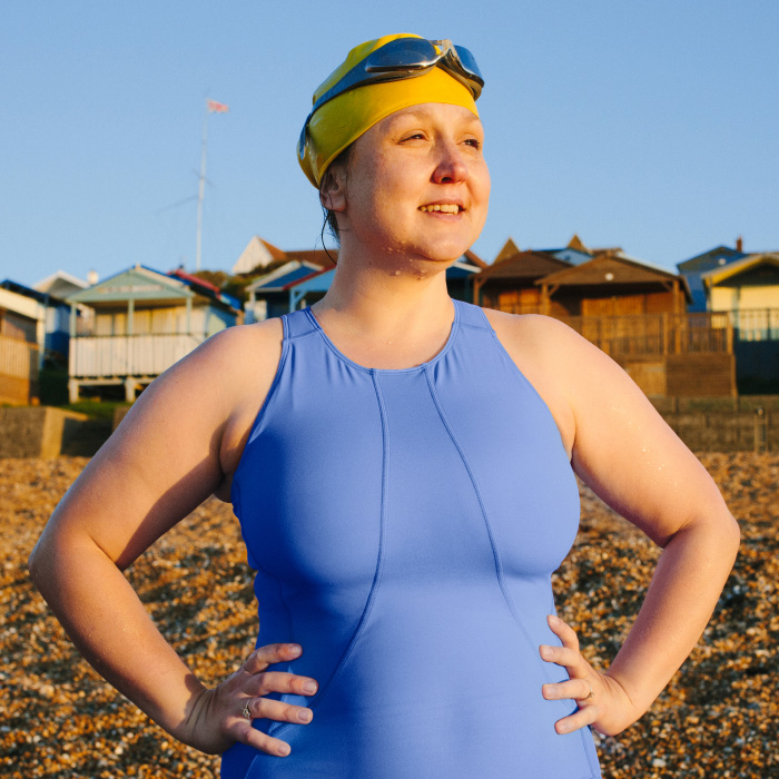 Frau im Schwimmoutfit am Strand bei Abendsonne