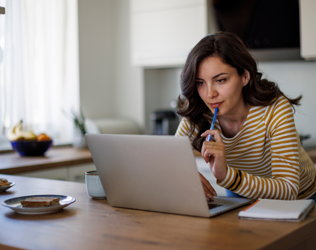 Eine Frau schaut in einer Küche auf ihren Laptop