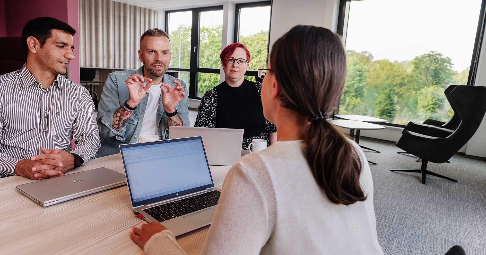 3 Mitarbeiter*innen der IT-Abteilung der Hanseatic Bank diskutieren mit der UX-Expertin über eine neue Funktion
