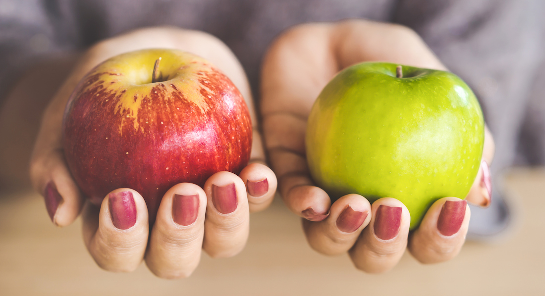 Unterschied Festgeld und Sparbrief: Eine Frau hält je einen roten und einen grünen Apfel in der Hand