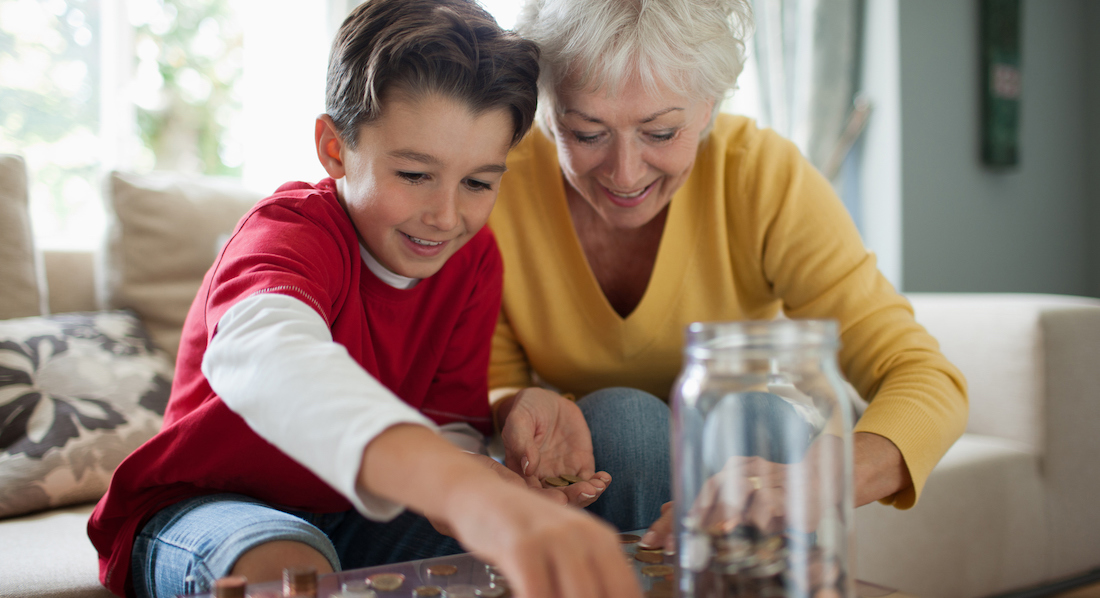 Junge und Großmutter zählen zusammen das Ersparte aus einem Glas mit Münzen