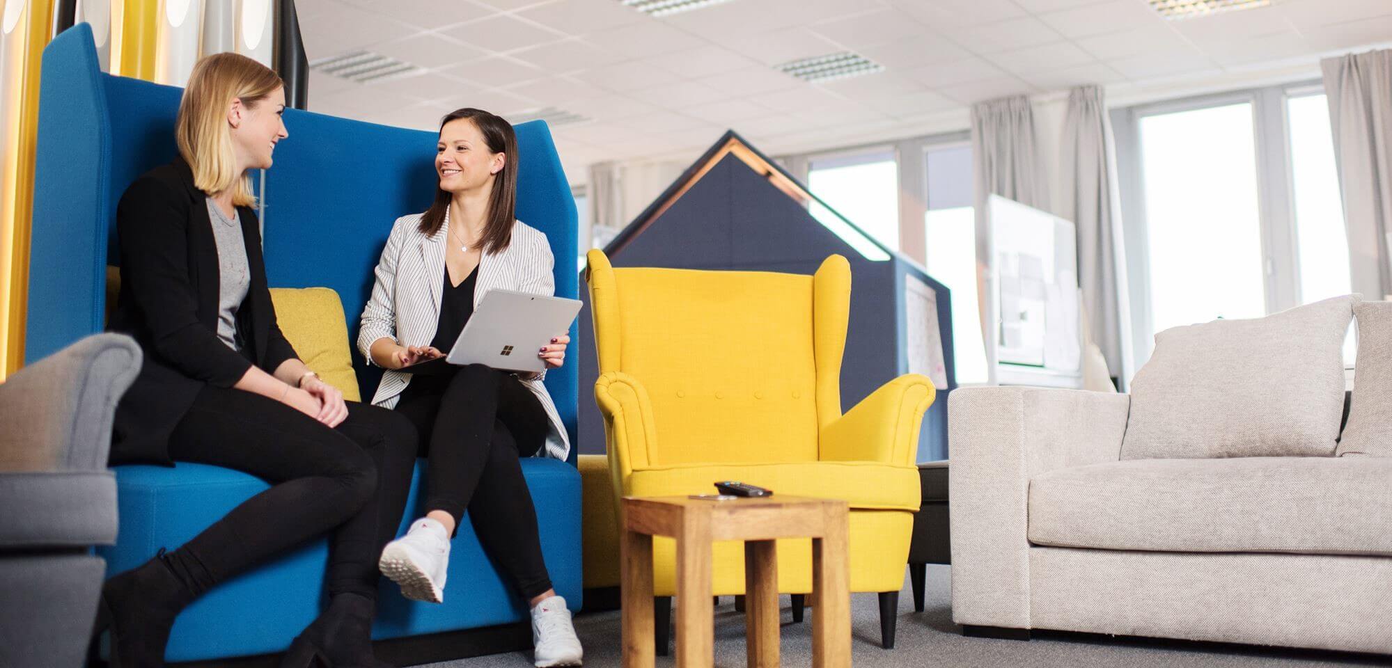 Zwei Personen sitzen in einem modernen Büro und tauschen sich aus.