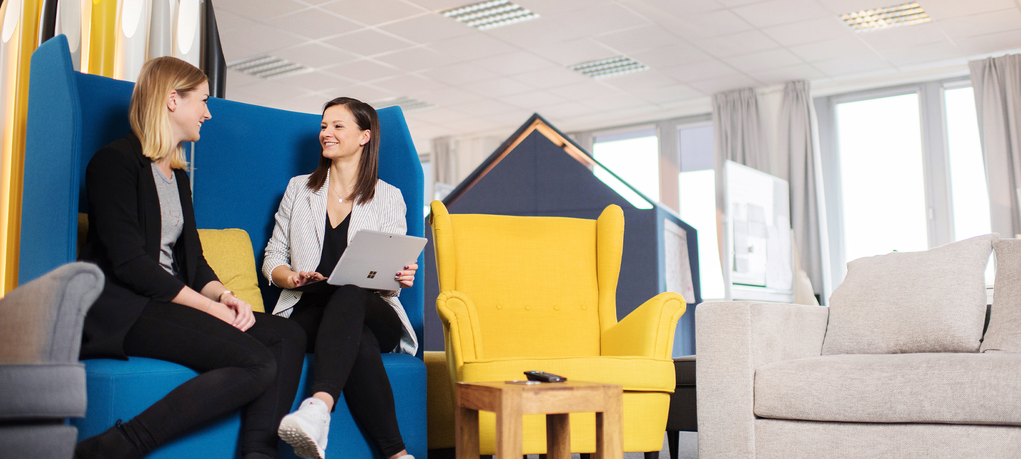 Zwei Personen sitzen in einem modernen Büro und tauschen sich aus.