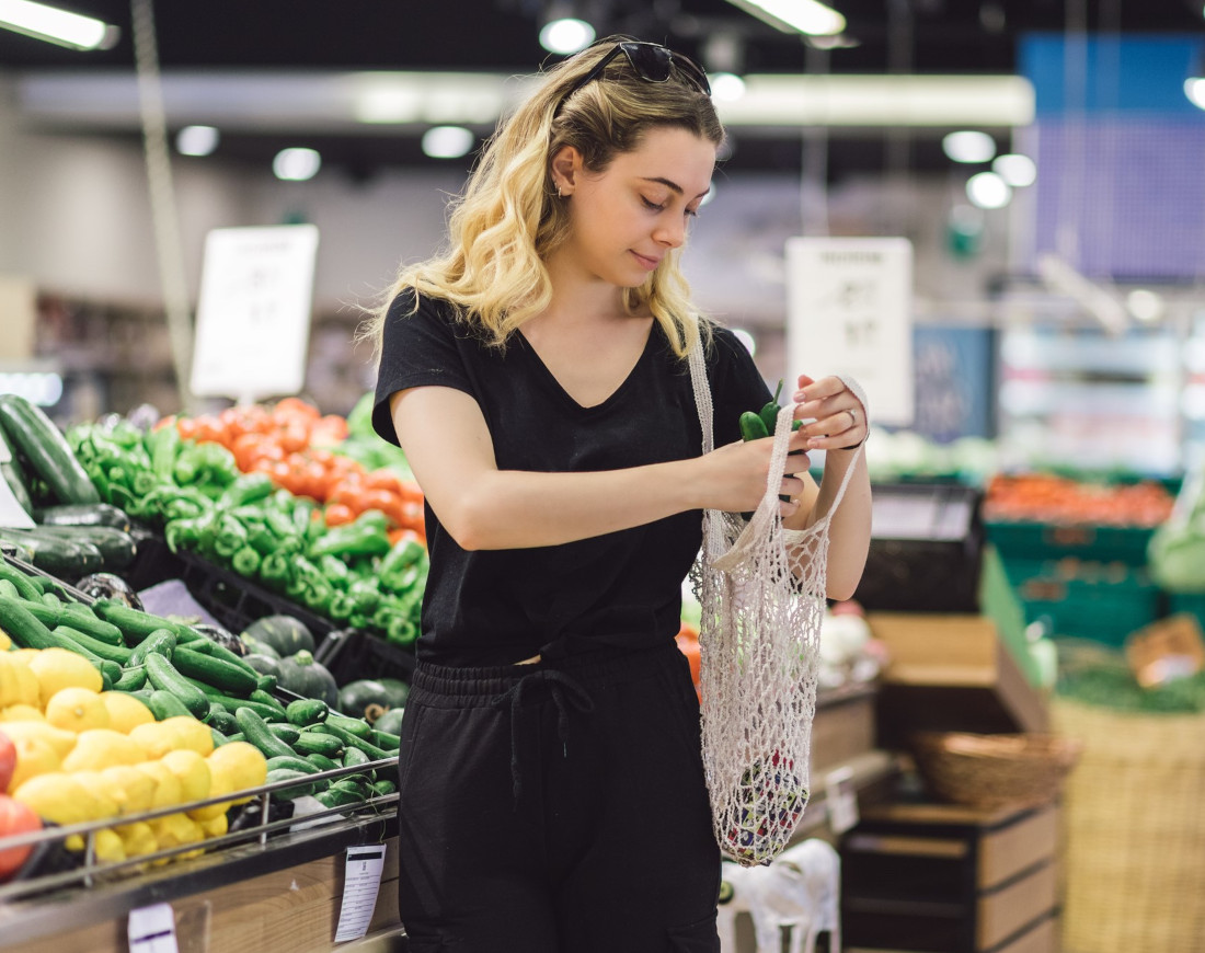 Eine Frau kauft im Supermarkt unverpacktes Gemüse ein