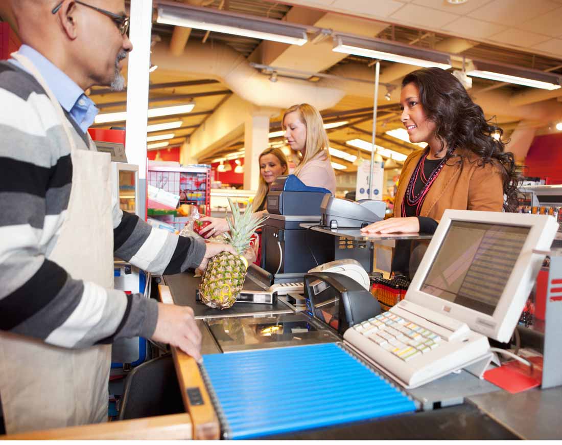 Frau steht mit ihren Einkäufen an der Supermarktkasse