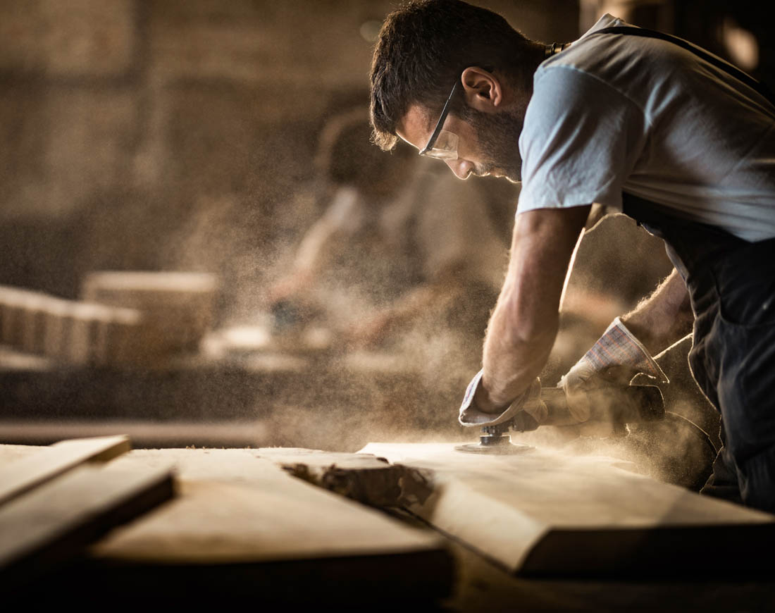 Tischler bearbeitet Holz mit einem Schleifgerät