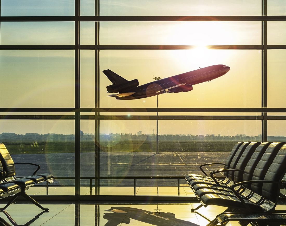 Blick aus einem leeren Flughafen Terminal auf ein abhebendes Flugzeug