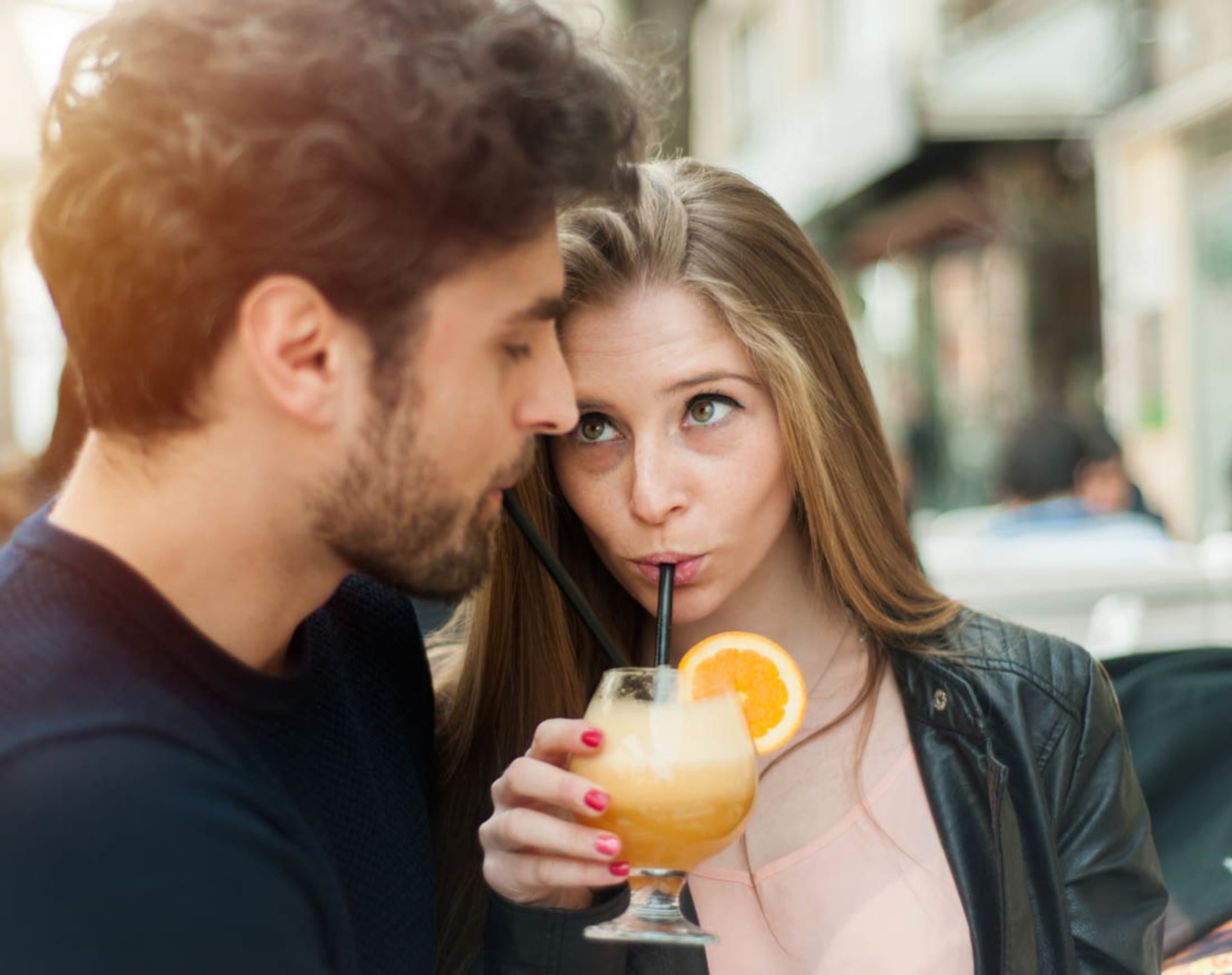 Pärchen trinkt gemeinsam aus einem Cocktailglas und macht sich Gedanken, ob aus getrennten Krediten ein gemeinsamer Kredit werden könnte.