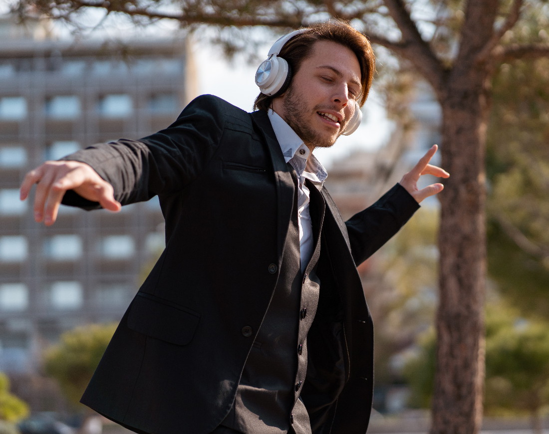 Mann im Geschäftsanzug trägt Kopfhörer und tanzt auf der Straße