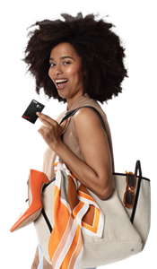 Frau trägt eine Einkaufstasche und hält begeistert die GenialCard Kreditkarte der Hanseatic Bank in ihren Händen