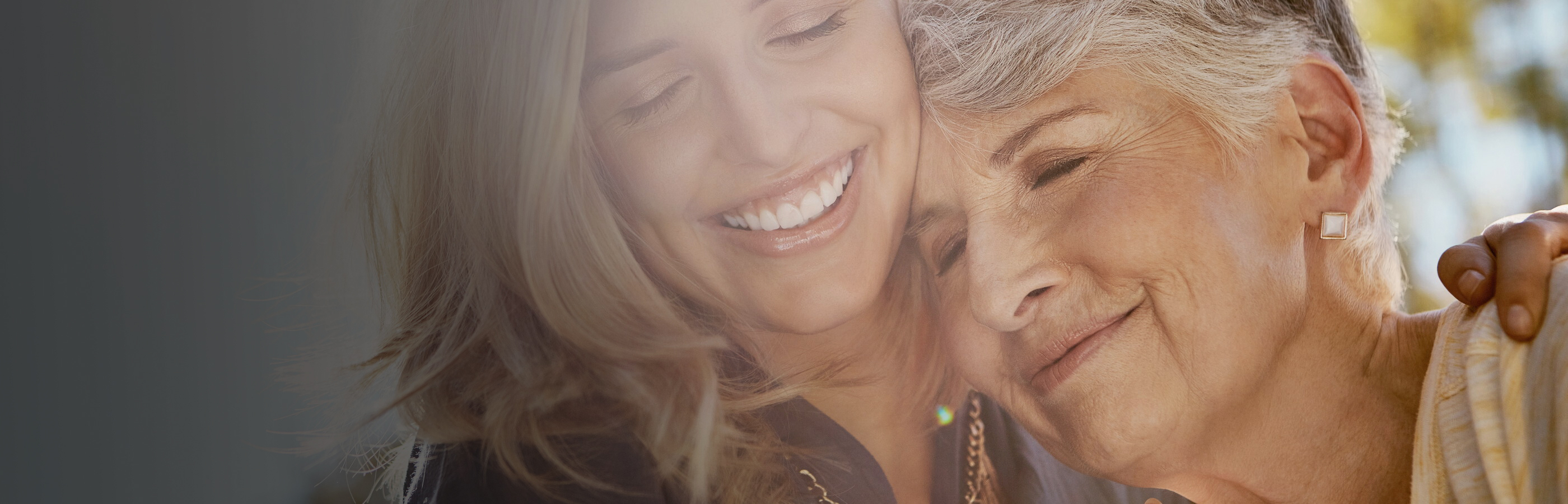 Frau hält ältere Frau im Arm, beide lächeln