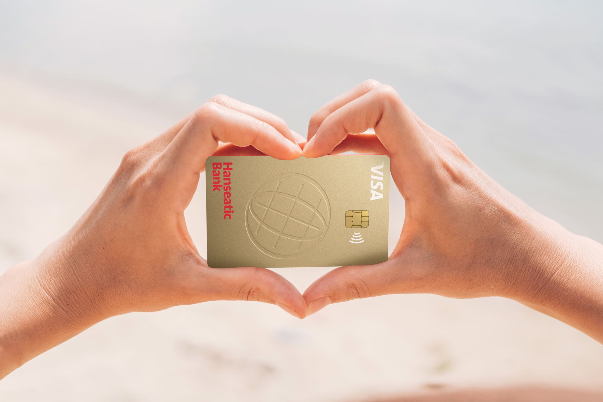 Hände formen ein Herz um die GoldCard Kreditkarte der Hanseatic Bank