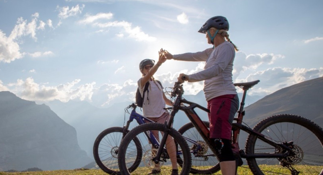 Zwei Radfahrerinnen auf E-Mountainbikes klatschen auf dem Berg ab