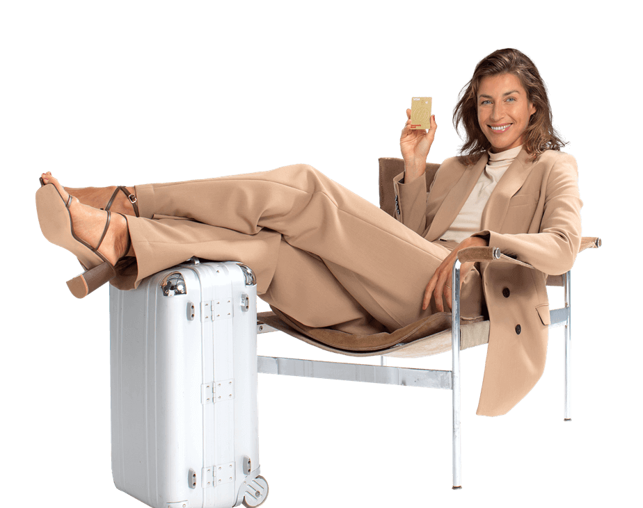 Weibliches Modell mit Koffer auf einem Stuhl präsentiert die Kreditkarte Goldcard der Hanseaticbank