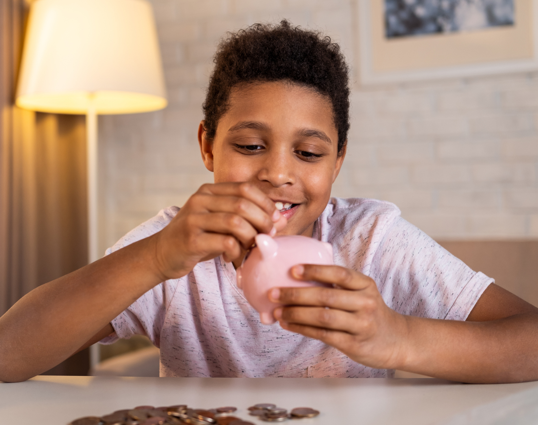 Farbiger Junge steckt lächelnd Geld in sein Sparschwein