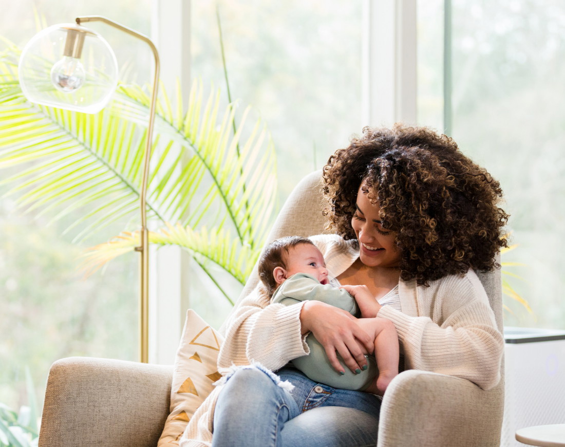 Eine Frau sitzt mit ihrem Baby auf einem Sessel