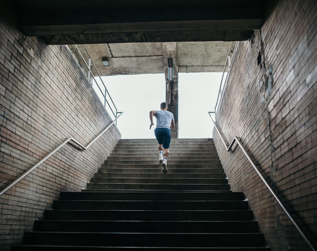 Ein Mann im Sportdress läuft eine lange Treppe hinauf