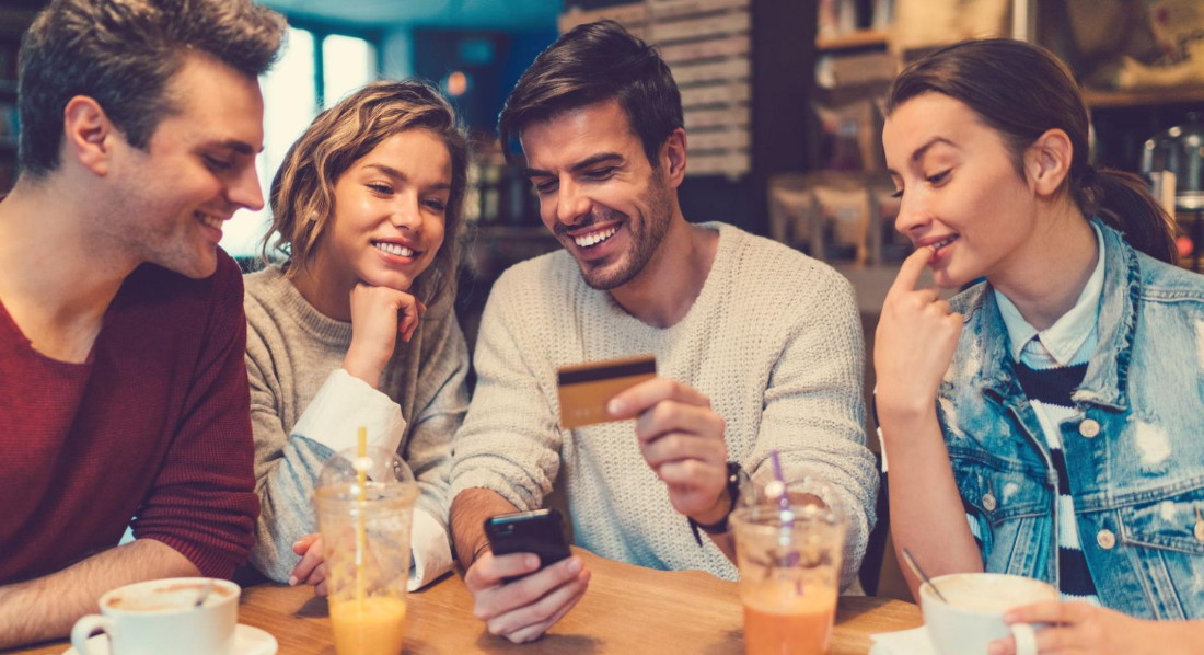 Eine Gruppe von Freunden kauft etwas auf dem Smartphone mit der Kreditkarte
